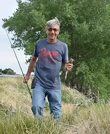 Jack Stadel standing in tall grass beside Wyoming trees